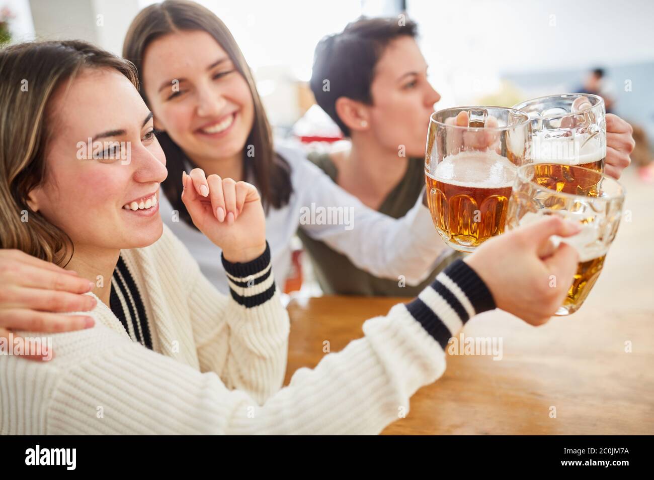 Glückliche Gruppe von Frauen beobachten gemeinsam Fußball und klicken gemeinsam auf Gläser Bier Stockfoto
