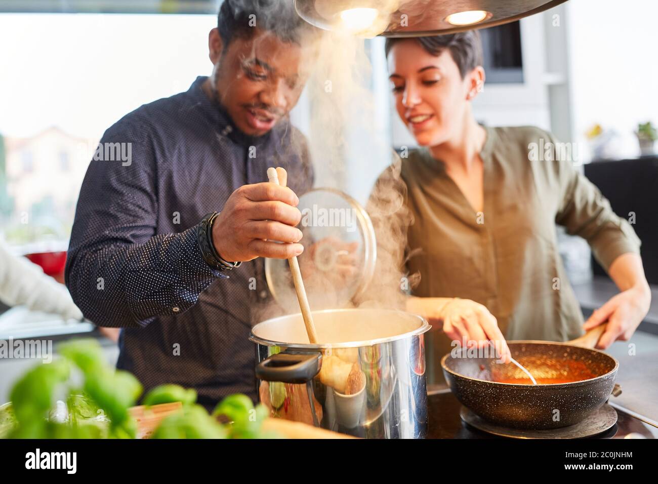 Freunde kochen Pasta mit Sauce zusammen in der Gemeinschaftsküche für gemeinsames Essen Stockfoto
