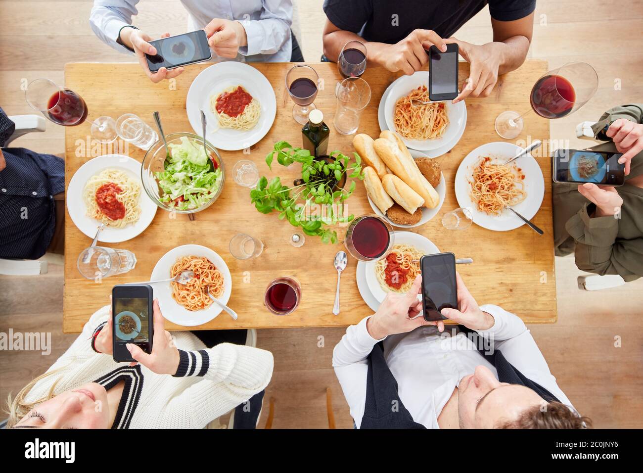Freunde nehmen Foodie Foto mit dem Smartphone von gemeinsamen Pasta-Mahlzeit mit Salat von oben Stockfoto
