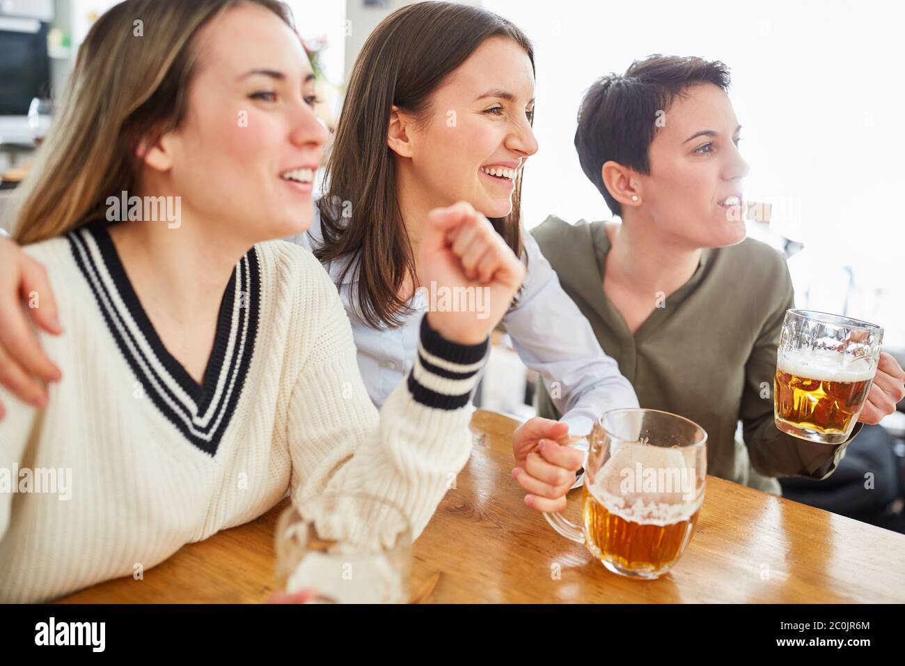 Eine Gruppe von Frauen gucken Fußball, trinken Bier und jubeln ihr Team an Stockfoto