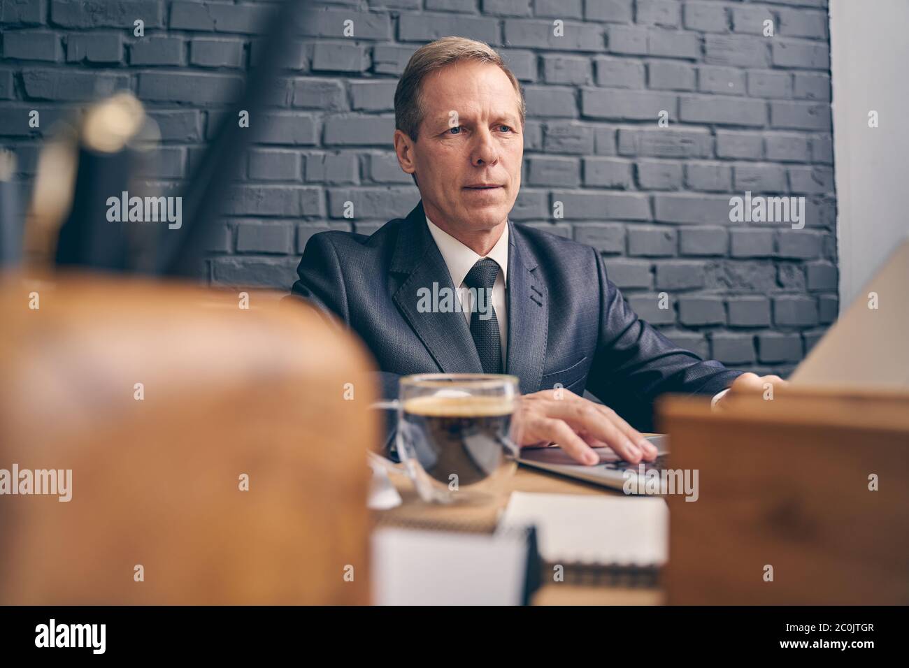 Freundlicher älterer Mann, der bei seiner Aufgabe bewusst arbeitet Stockfoto