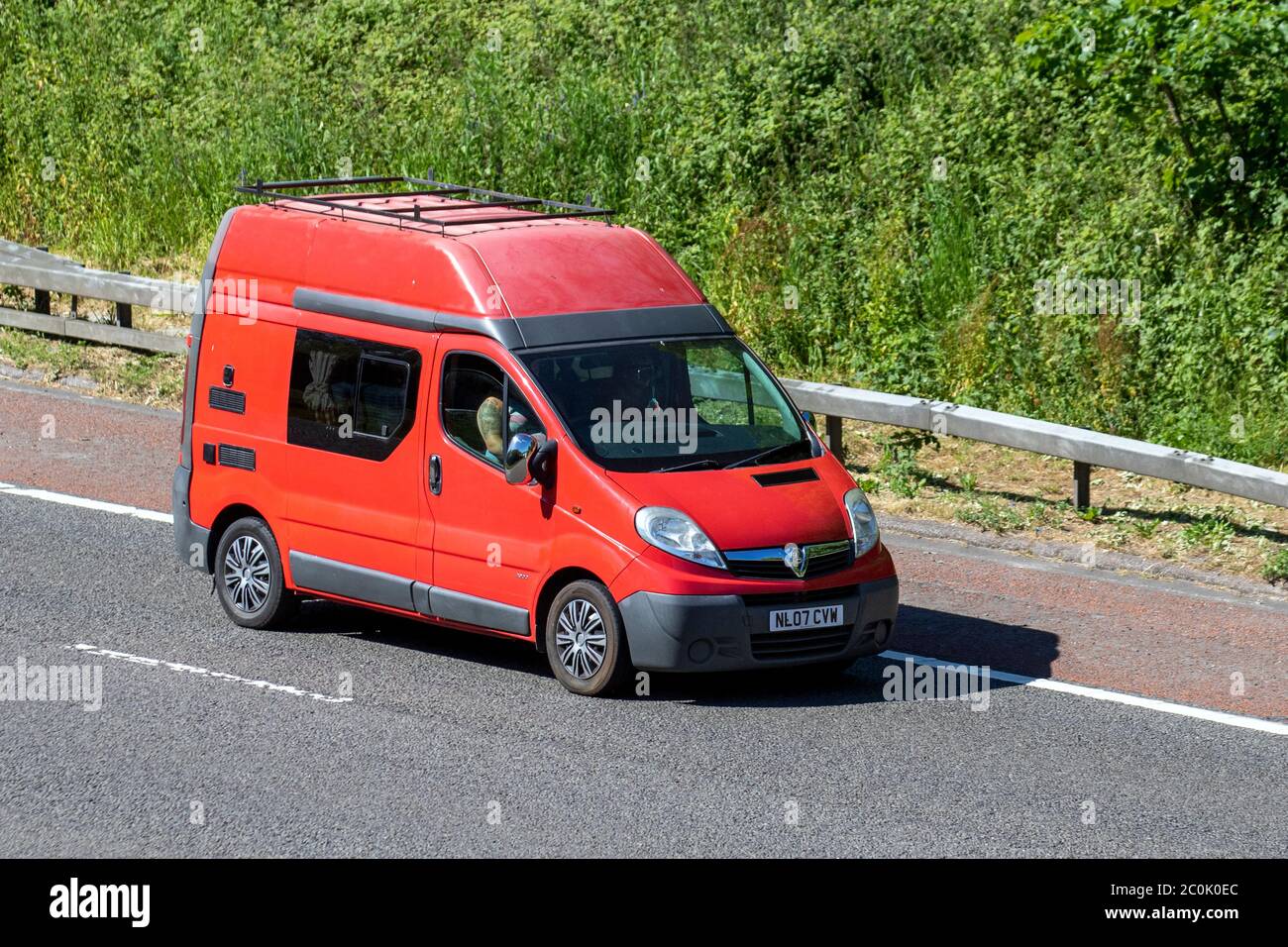 Tätowierte Mann fahren 2007 rot Vauxhall Combo CDTI; Fahrzeug Verkehr Moving Fahrzeuge, Autos & Vans Fahren Fahrzeug auf britischen Straßen, Motoren, Fahren auf der Autobahn M6 Stockfoto