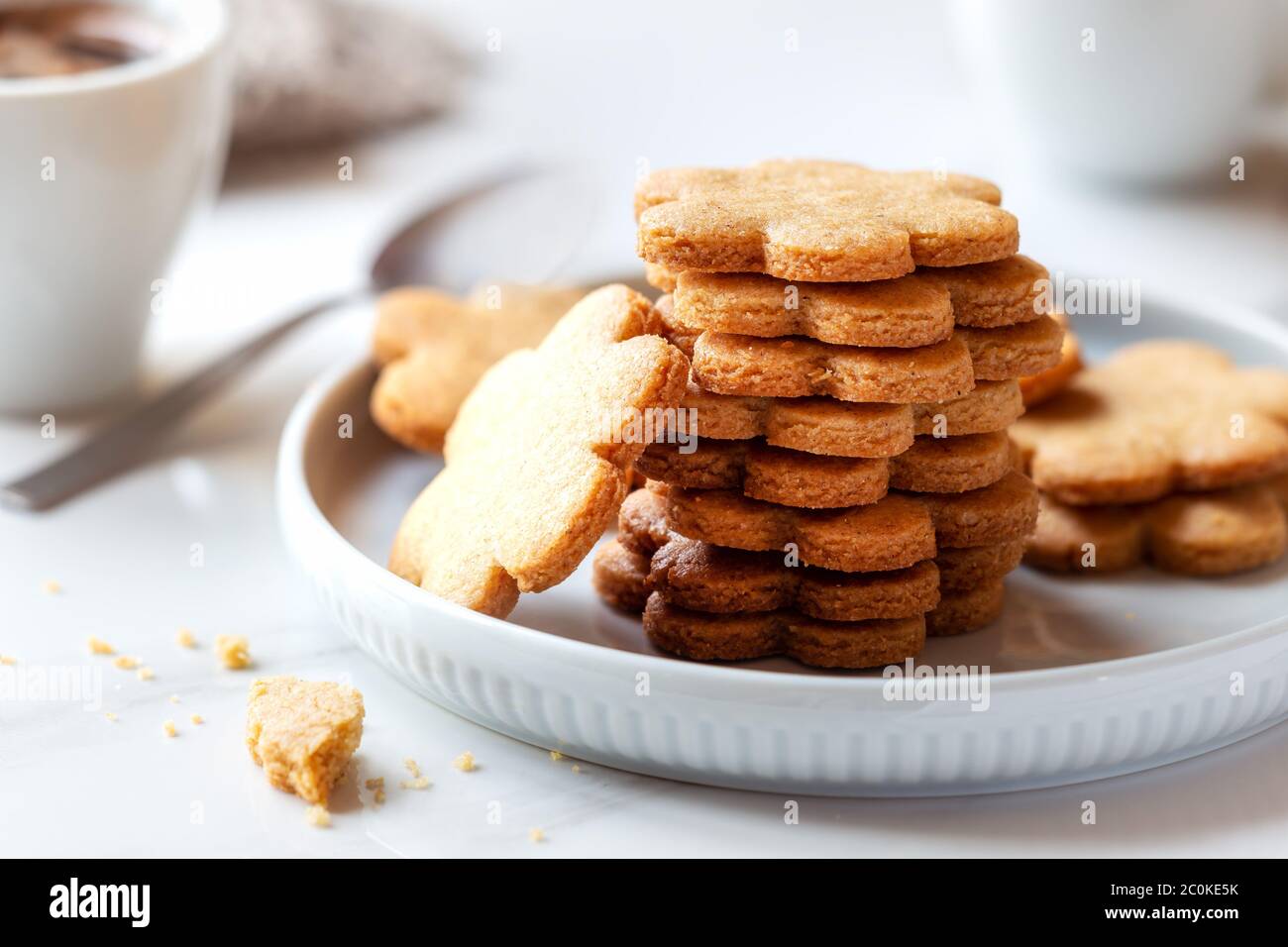 Frisch gebackene hausgemachte Kekse zum Frühstück mit einer Tasse Kaffee im Hintergrund. Konzept „Guten Morgen“ Stockfoto