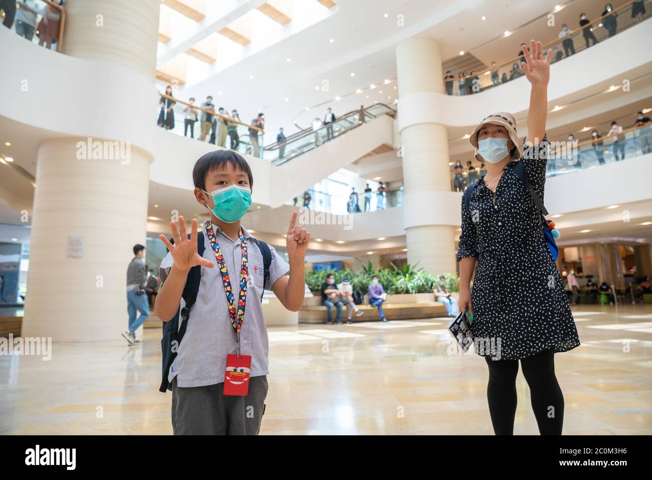 Ein Kinderproteger und seine Mutter gestikulierten die fünf Forderungen, Nicht weniger' Protestmotto während der Demonstration.Pro Demokratie Demonstranten veranstalteten eine Demonstration im Einkaufszentrum Pacific Place im Central District von Hong Kong, um den ersten Jahrestag des Starts der groß angelegten Anti-Regierung-Bewegung durch den vorgeschlagenen Auslieferungsgesetz ausgelöst, das viele glauben, wird Als politisches Instrument benutzt werden, um Chinas politische Feinde in Hongkong zum Schweigen zu bringen. Stockfoto