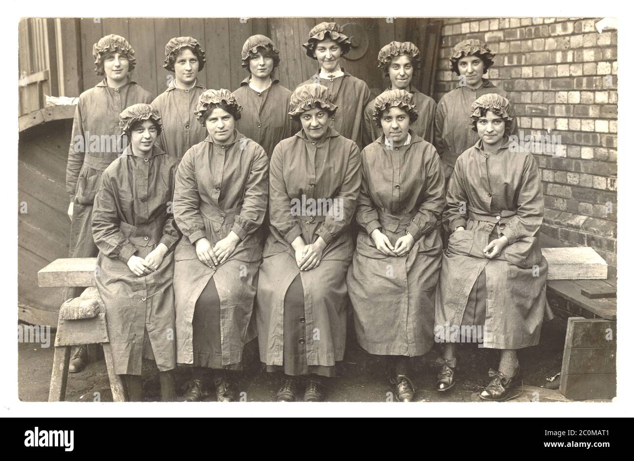 Originalpostkarte aus der Zeit des 1. Weltkriegs mit Frauen, die in der Werft oder bei Munitionsarbeitern arbeiten, mit elastischen Kappen und schwer entflammbarem „National Shell Overall“, Overalls, um 1915, Großbritannien Stockfoto