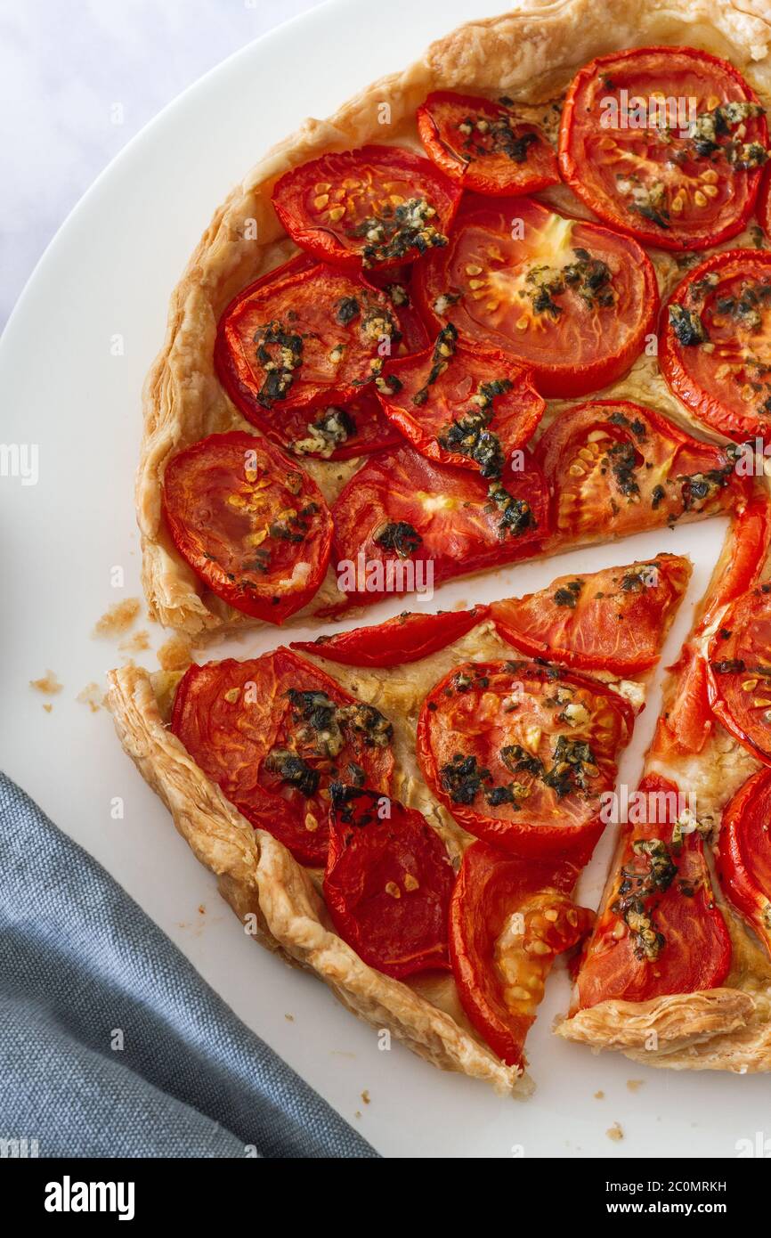 Tomate und Senftorte mit geschnittener Scheibe auf einem großen weißen Teller Stockfoto