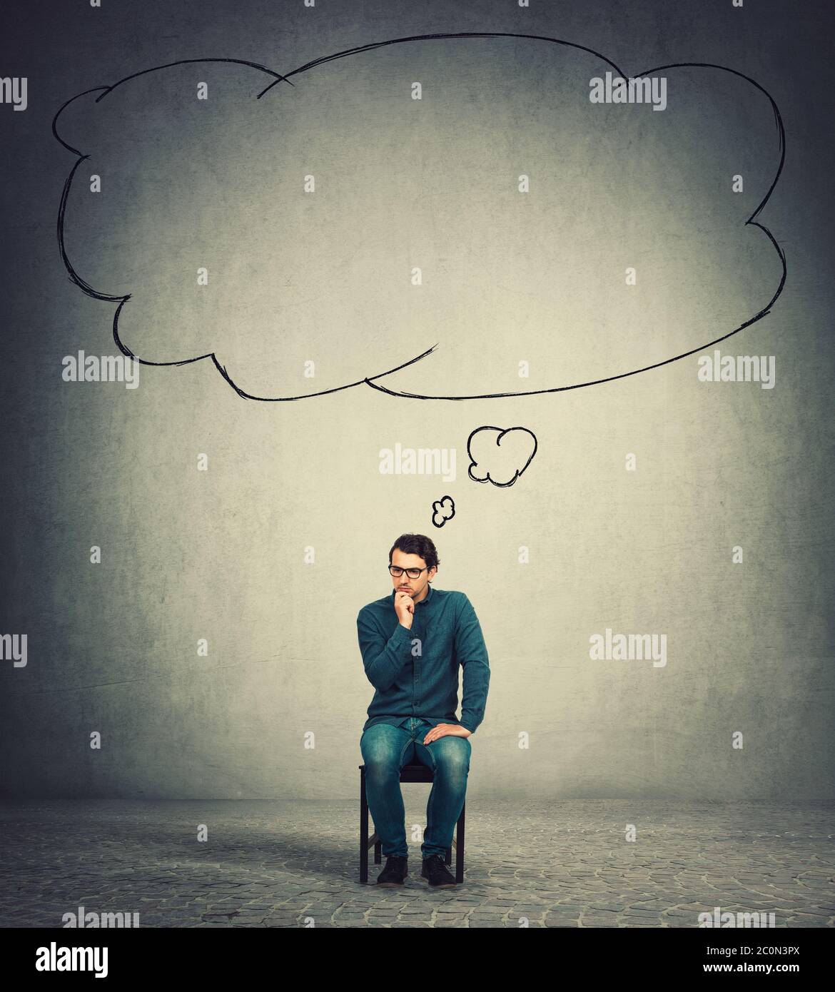 Nachdenklicher Geschäftsmann hält die Hand unter dem Kinn, sitzt auf einem Stuhl, denkt konzentriert, wie eine leere Gedankenblase aus seinem Kopf kommt. Mitarbeiter und Stockfoto