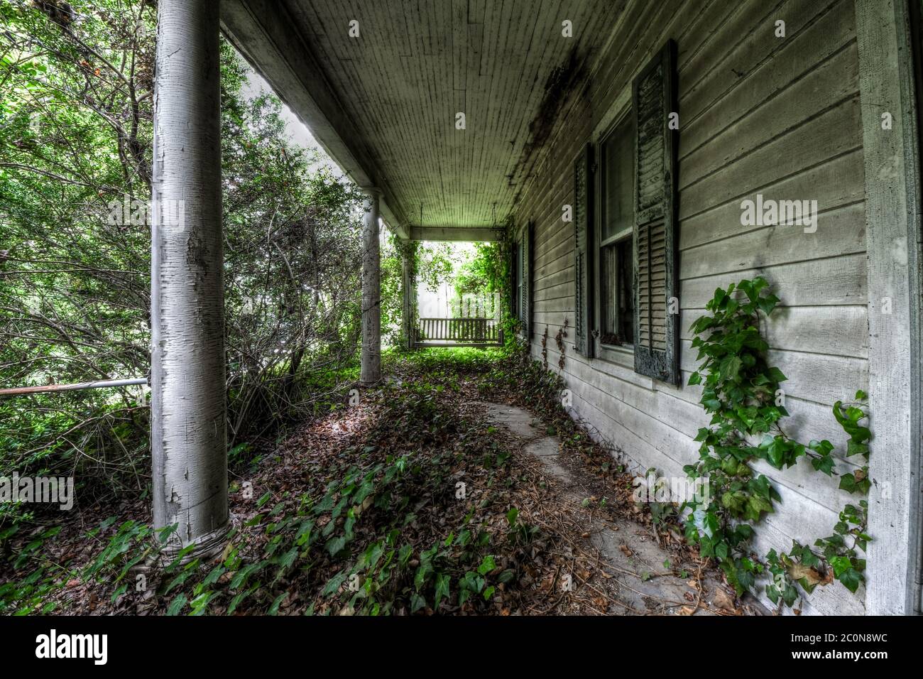 Veranda Schaukel mit Überwuchs auf der Veranda eines verlassenen Hauses Stockfoto