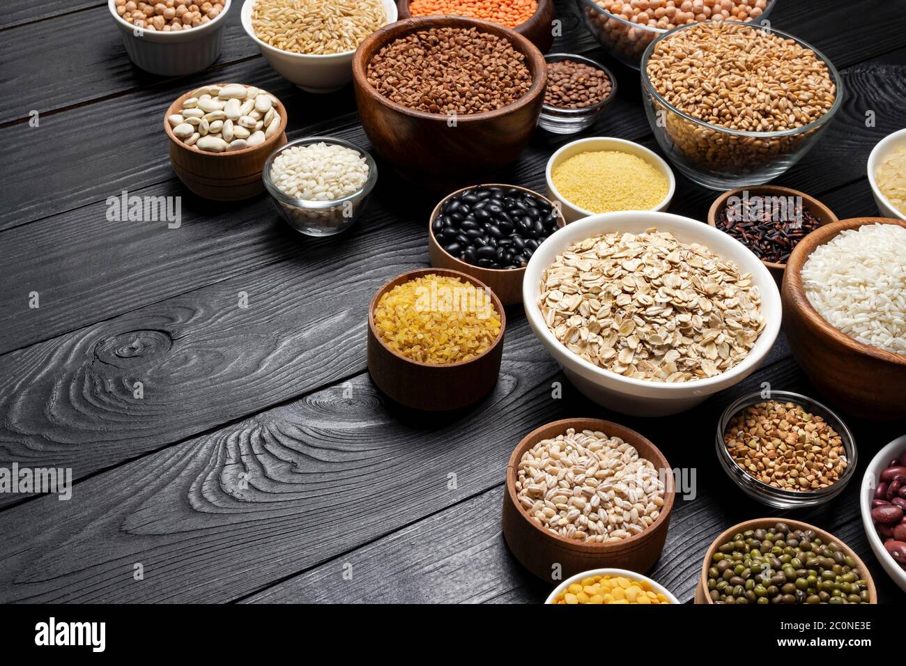 Getreide, Körner, Samen und Grütze schwarze hölzerne Hintergrund Stockfoto