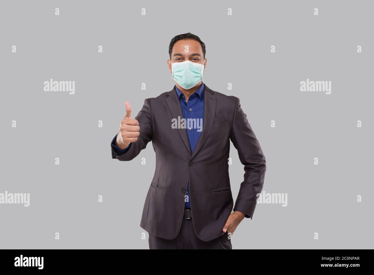 Geschäftsmann zeigt, wie man medizinische Maske und Handschuhe trägt isoliert. Indian Business man stehend Thump up Zeichen Stockfoto