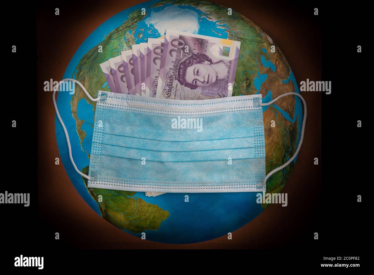 Globale Coronavirus-Pandemie und wirtschaftlicher Crash. Virus Facemask enthält britische Banknoten mit einem Hintergrund der Welt Stockfoto