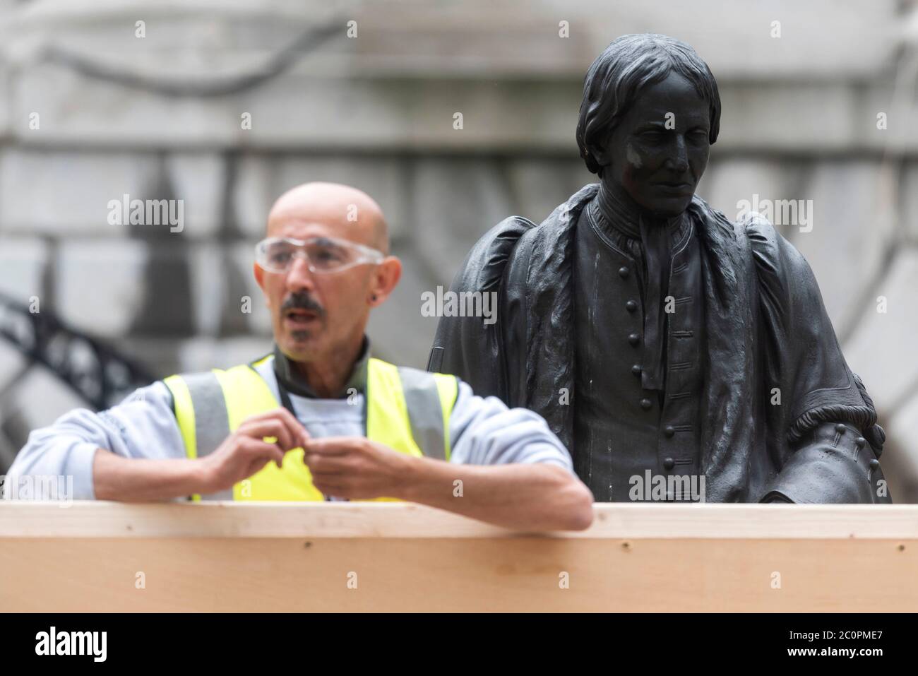 London, Großbritannien. Juni 2020. Ein Arbeiter geht am 12. Juni 2020 in die Statue von Thomas Guy im Guy's Hospital in London, Großbritannien. Wichtige Statuen und Denkmäler in London, einschließlich des Cenotaphs in Whitehall, Statuen von Winston Churchill und Nelson Mandela, sollen vor geplanten Black Lives Matter Protesten abgedeckt und geschützt werden, sagte Bürgermeister Sadiq Khan am Freitag. Quelle: Ray Tang/Xinhua/Alamy Live News Stockfoto