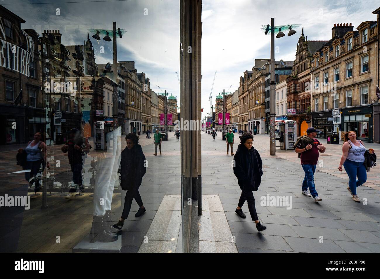 Glasgow, Schottland, Großbritannien. 12. Juni 2020. Blick auf die Menschen in der Buchanan Street Fußgängerzone Einkaufszone spiegelt sich in Schaufenster. Obwohl die Geschäfte in England nächste Woche wieder eröffnet werden können, wird in Schottland die Sperre nicht so schnell entspannt, da noch mehrere Wochen Restriktionen zu erwarten sind. Geschäfte und Geschäfte bleiben geschlossen und die Straßen sind sehr ruhig. Iain Masterton/Alamy Live News Stockfoto