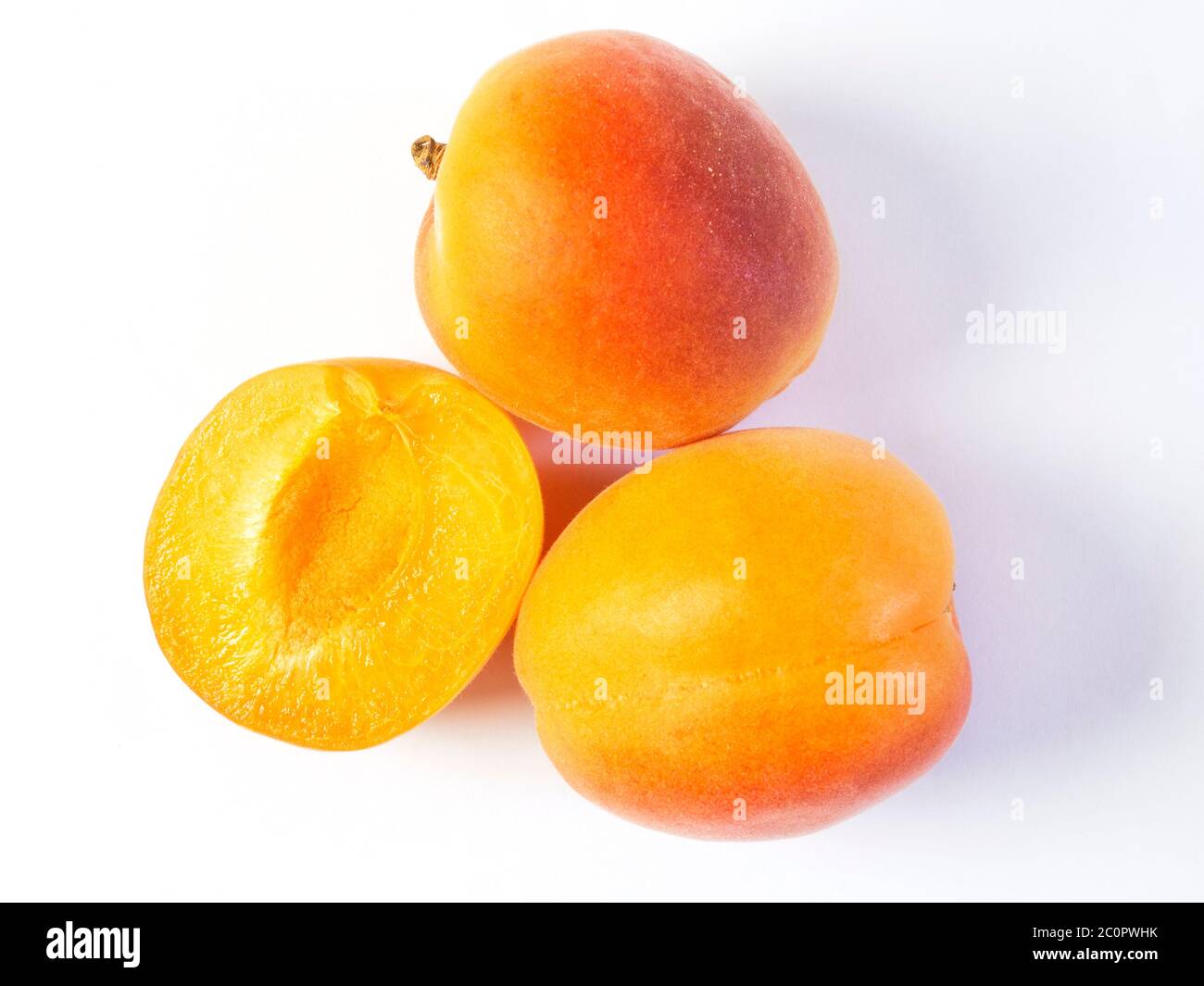 Zwei ganze frische Aprikosen und eine halbe Aprikose auf weißem Hintergrund Stockfoto