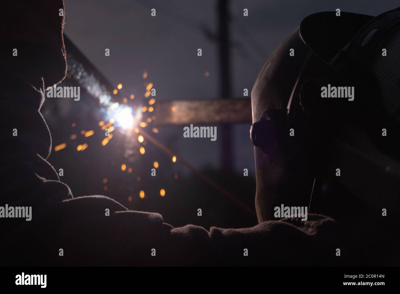 Arbeiter mit Schutzmaske Schweißen Metall und die Produktion von Rauch und Funken. Lichtbogenschweißen Stockfoto