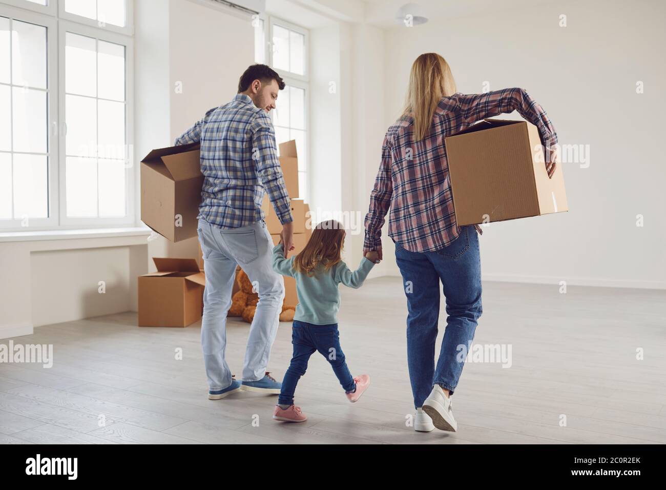 Glückliche Familie mit Kindern, die in einem neuen Mehrfamilienhaus mit Kisten umziehen. Stockfoto
