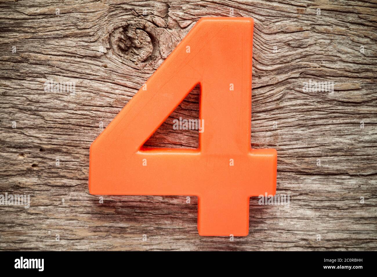 Orange Nummer vier auf dem hölzernen Hintergrund Stockfoto