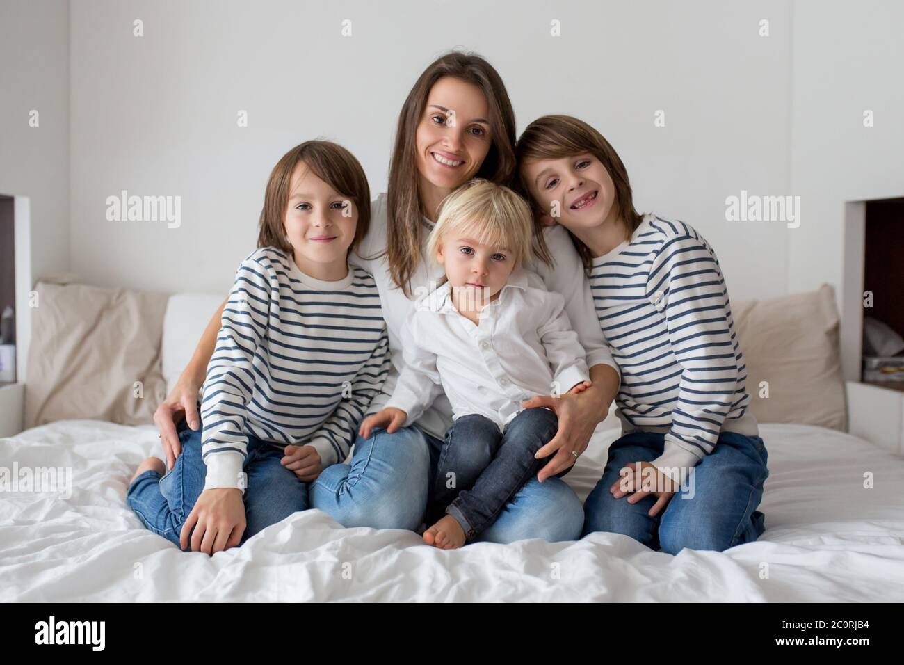 Glückliche Mutter und ihre Kinder auf einem Bett liegend Stockfoto