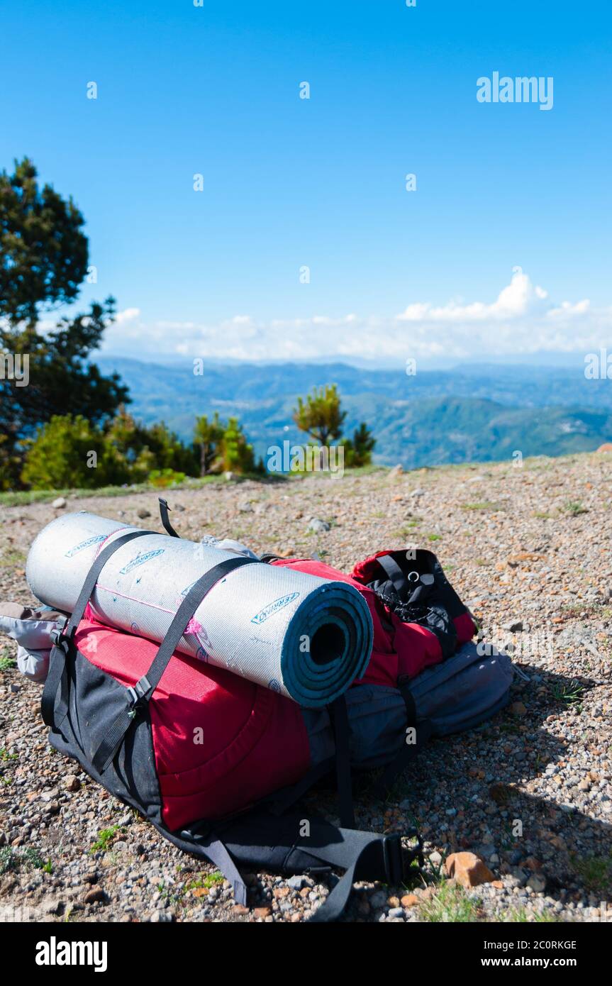Rot Rucksack mit Isomatte legt auf felsigen Boden vor Berg Tajamulco und blauer Himmel mit Wolken Stockfoto