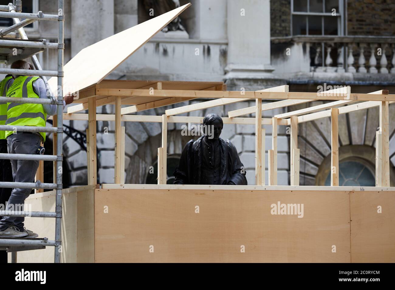 London, Großbritannien. - 12. Juni 2020: Arbeiter decken die Statue von Thomas Guy vor der Entfernung von seiner Position in einem Innenhof des Krankenhauses, das er gefunden half. Thomas Guy soll sein Vermögen aus Aktien in einem Unternehmen gemacht haben, das im Sklavenhandel beteiligt war. Stockfoto