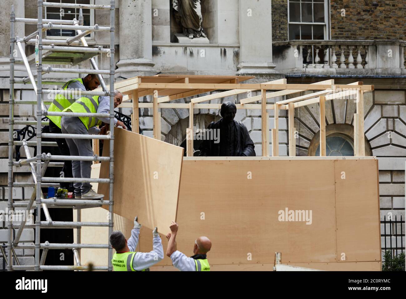London, Großbritannien. - 12. Juni 2020: Arbeiter decken die Statue von Thomas Guy vor der Entfernung von seiner Position in einem Innenhof des Krankenhauses, das er gefunden half. Thomas Guy soll sein Vermögen aus Aktien in einem Unternehmen gemacht haben, das im Sklavenhandel beteiligt war. Stockfoto