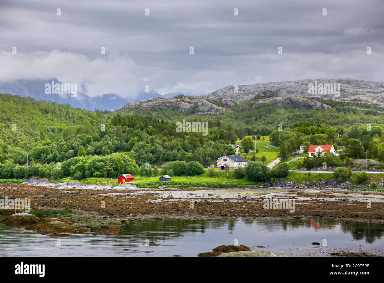 Schöne Landschaft zusammen mit Wasser Rand, mit einem Dorf, Kirche & Berge, Saltstraumen, Gemeinde Bodo, Nordland County, Norwegen. Stockfoto