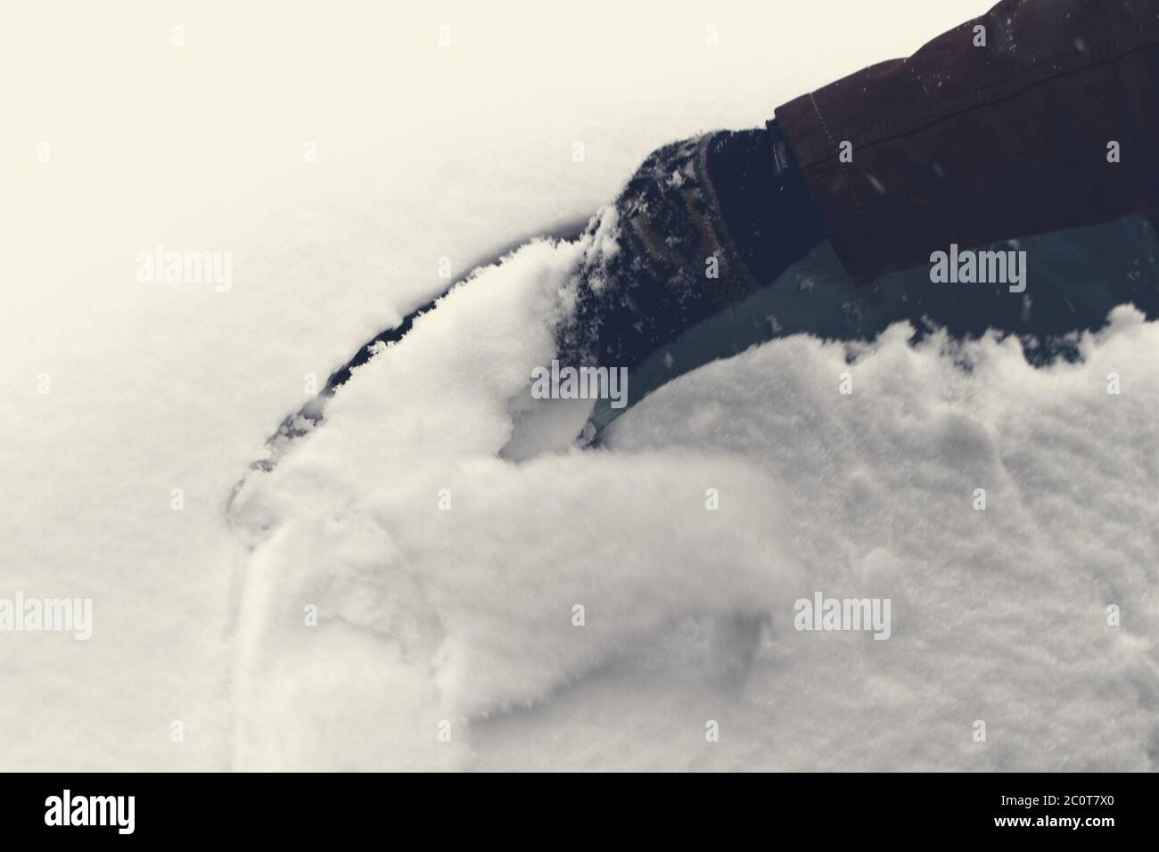 Mann kratzt Schnee und Eis vom Autofenster Stockfoto
