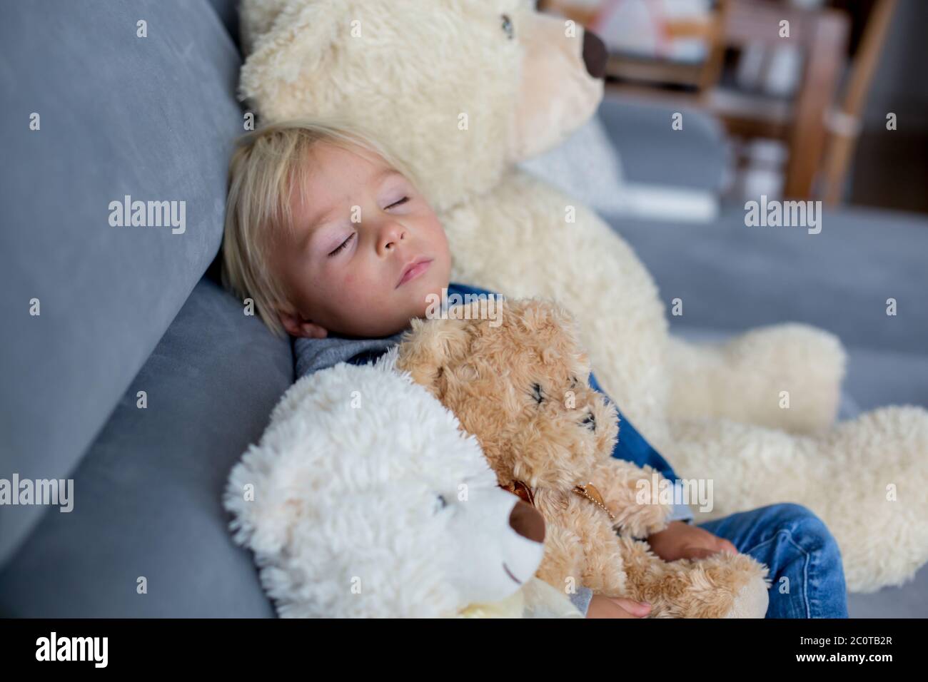 Blonde Kleinkind Junge, schlafen mit vielen Teddybären am Nachmittag auf dem Sofa Stockfoto