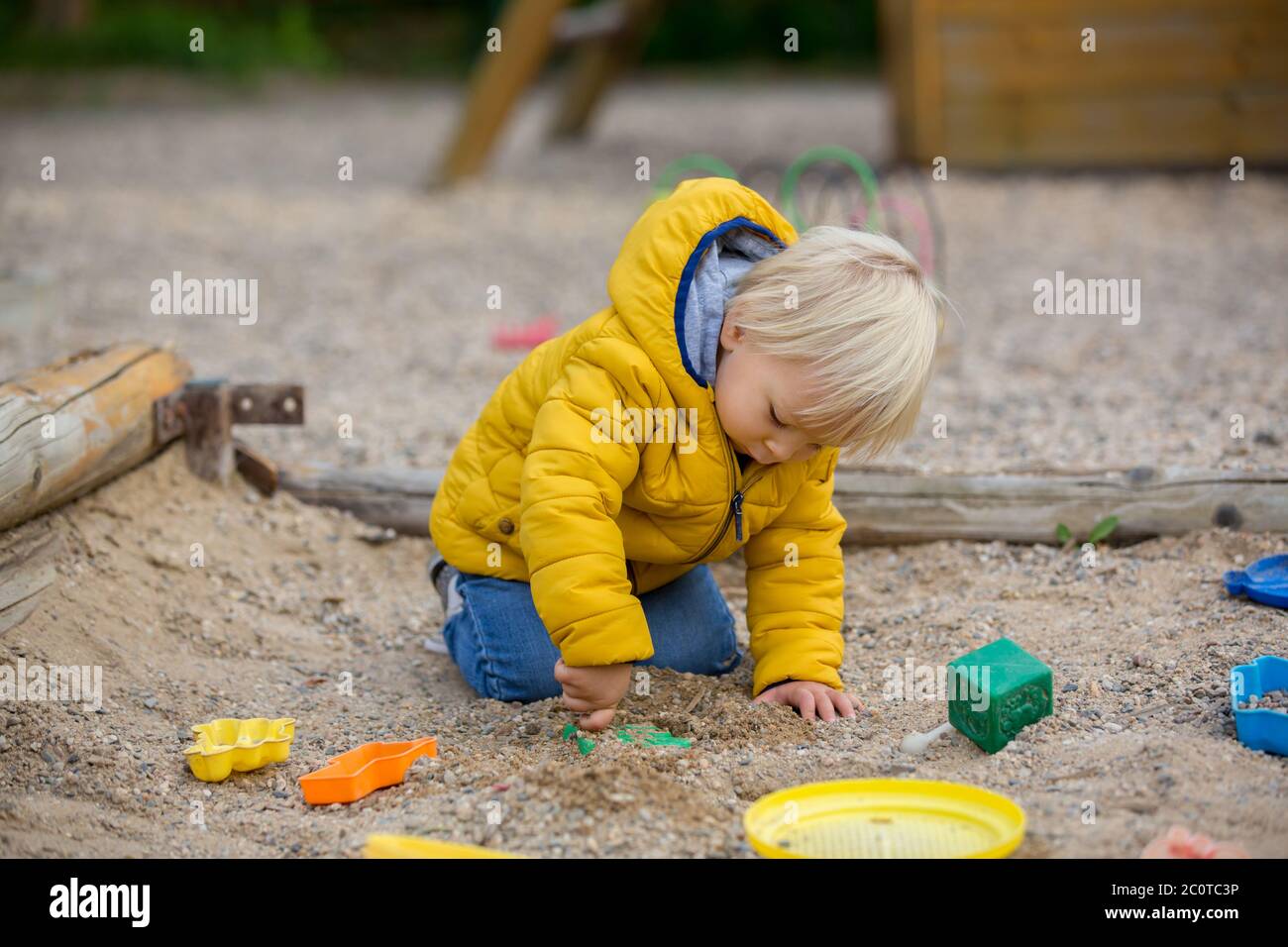 Blonde kleine Kleinkind Kind in gelber Jacke, spielen auf dem Spielplatz,  Herbst sonnigen Tag Stockfotografie - Alamy
