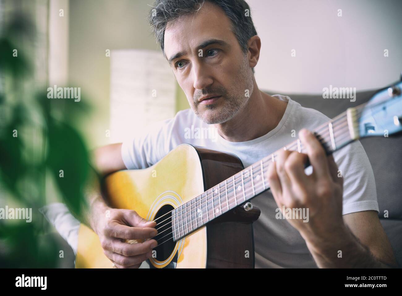 Detail eines Musikers Mann spielt akustische Gitarre mit weißen Kurzarm-Shirt im Zimmer zu Hause Stockfoto