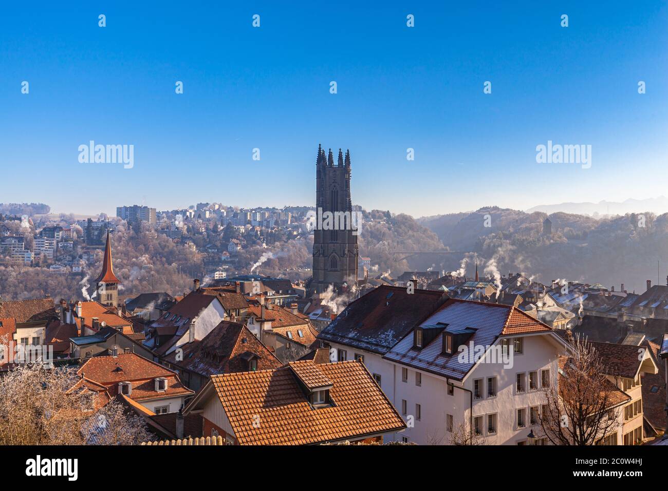 Luftpanorama von Freiburger Stadtbild an einem sonnigen Wintertag mit Freiburger Dom und frostbedeckten Gebäuden und blauem Himmel im Hintergrund, Schweiz Stockfoto