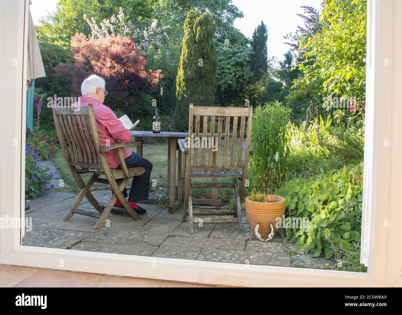 Ein älterer Mann saß in einem Oxfordshire Garten und entspannte sich mit einem Oxfordshire Bitter Ale an einem Summers Abend während der COVID-19 Pandemie. Stockfoto