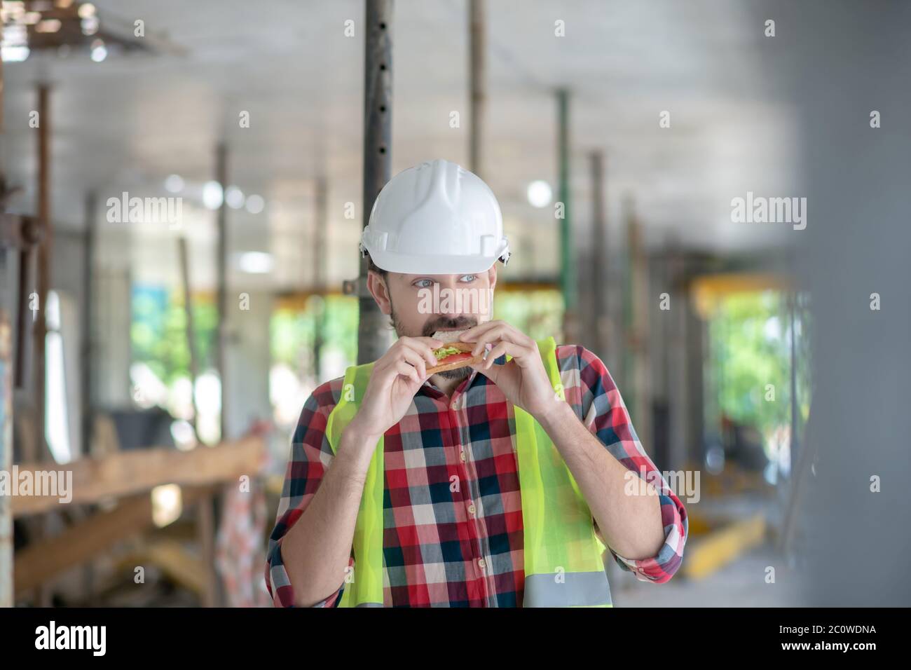 Bauarbeiter in gelben Weste und Helm Essen Sandwich Stockfoto