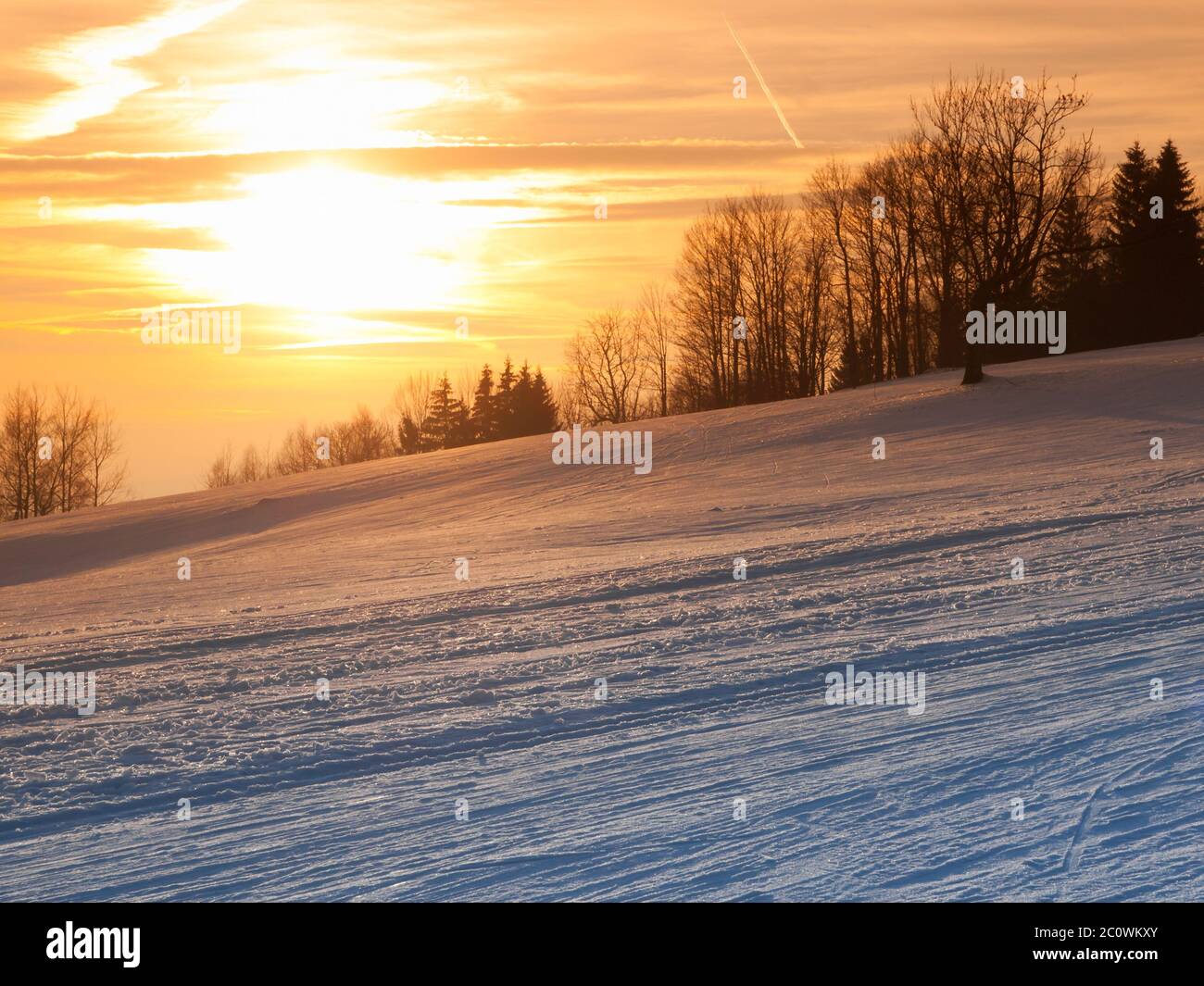 Winteruntergang in den Bergen mit Langlaufloipe Stockfoto
