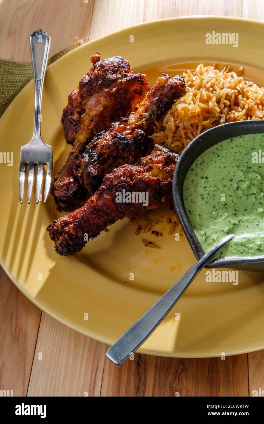 Peruanische Hühnerschenkel mit Aji verde grüner Koriander-Sauce und gebratenem Reis Stockfoto