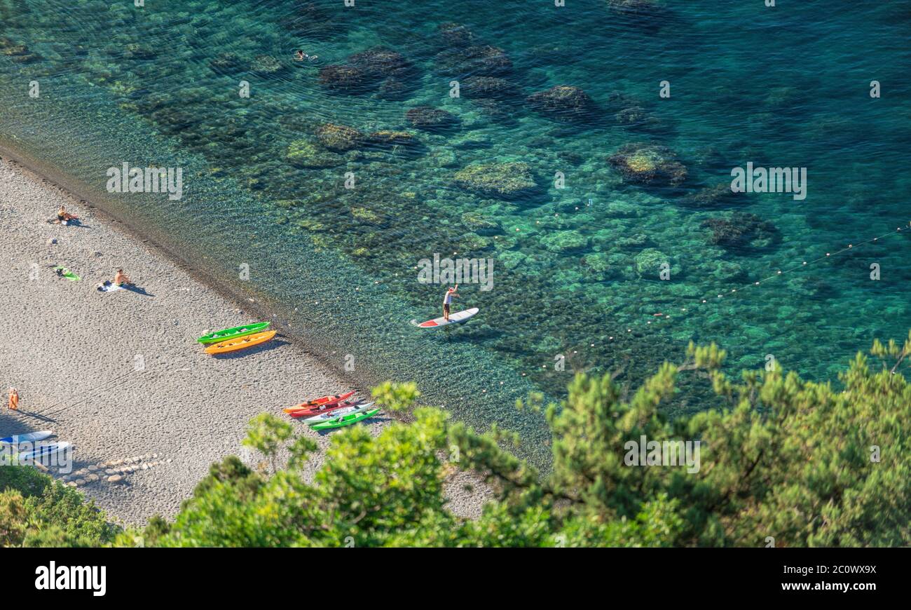 Starke Männer treiben an einem sonnigen Morgen auf SUP-Boards im kristallklaren Wasser. Luftaufnahme der Männer überquert die Bucht mit dem Paddelbrett. Stockfoto