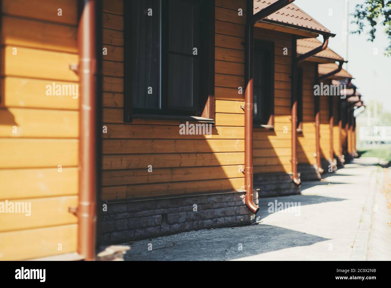 Eine Reihe von gelben gleichen Holz einstöckigen Häusern in einer Jugendherberge oder Pension mit Dreieckdächern, Fallrohre und Einzelfenster, sonnigen Tag Stockfoto