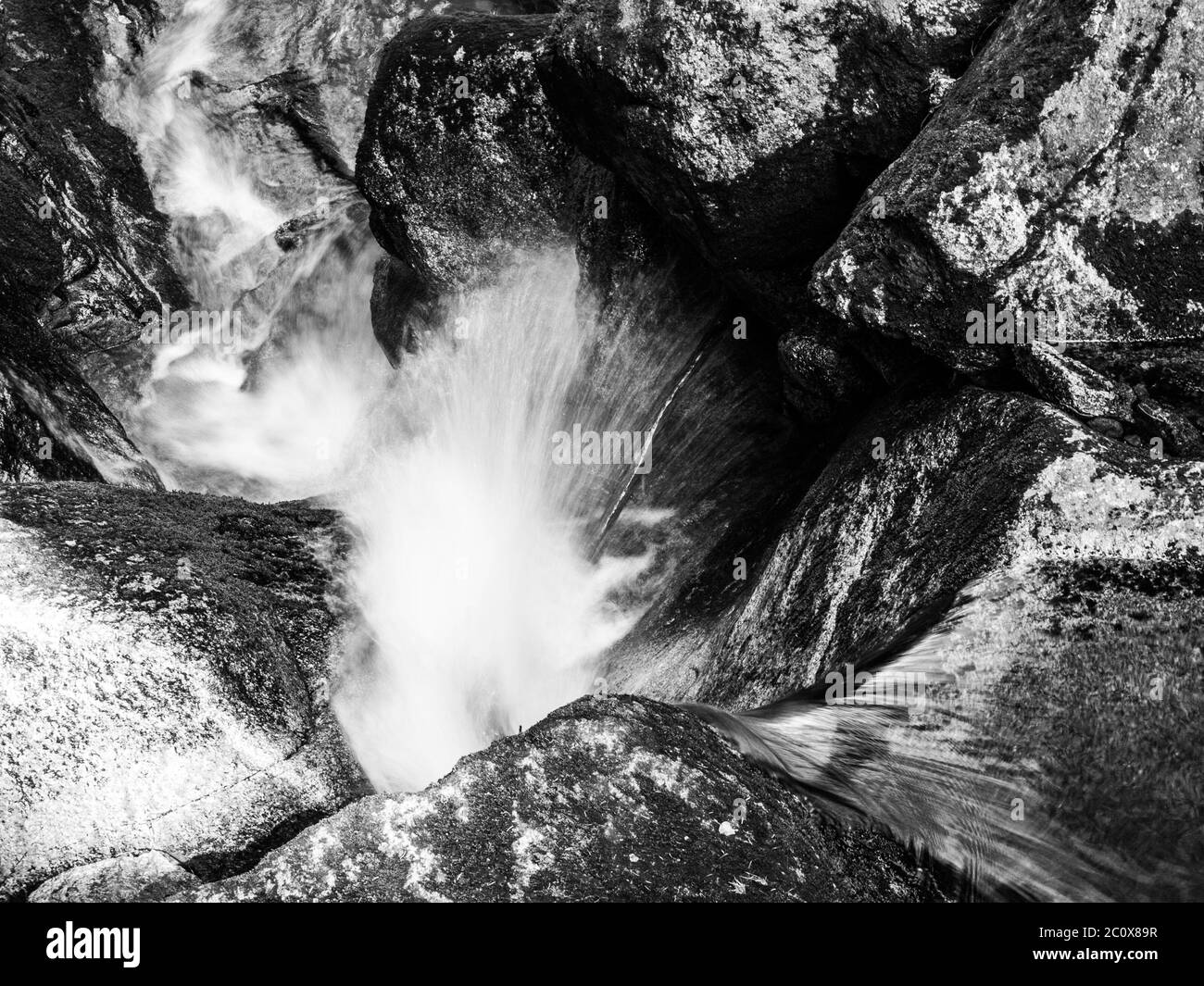 Wasserfallkaskade des kleinen Baches zwischen moosigen Steinen. Langzeitbelichtung Schwarzweiß-Bild. Stockfoto