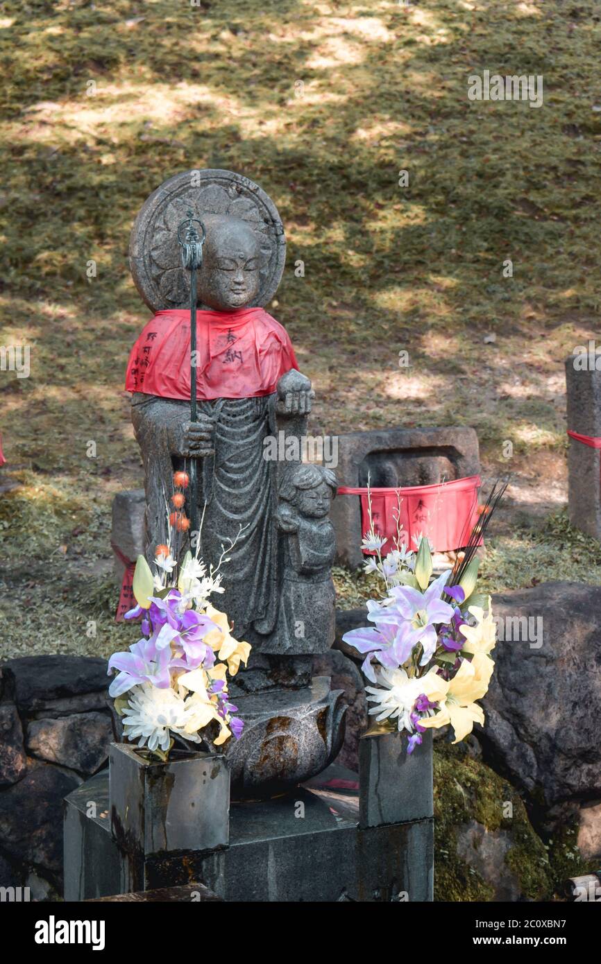 Statuen japanischer Shinto-Geister, die in festliche Dekorationen und Blumen gekleidet sind Stockfoto