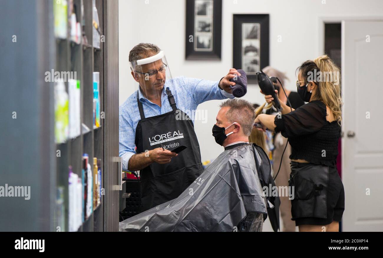 Brantford, Kanada. Juni 2020. Ein Barbier (L) mit Schutzschild schneidet einem Kunden am 12. Juni 2020 in einem Friseursalon der Lynden Park Mall in Brantford, Ontario, Kanada, die Haare. Die Provinz Ontario erlaubte den meisten Regionen außerhalb der Toronto und Hamilton-Gebiete, am Freitag während des COVID-19-Ausbruchs weitere Geschäfte wieder zu eröffnen, einschließlich Restaurantterrassen, Friseursalons und Einkaufszentren. Quelle: Zou Zheng/Xinhua/Alamy Live News Stockfoto