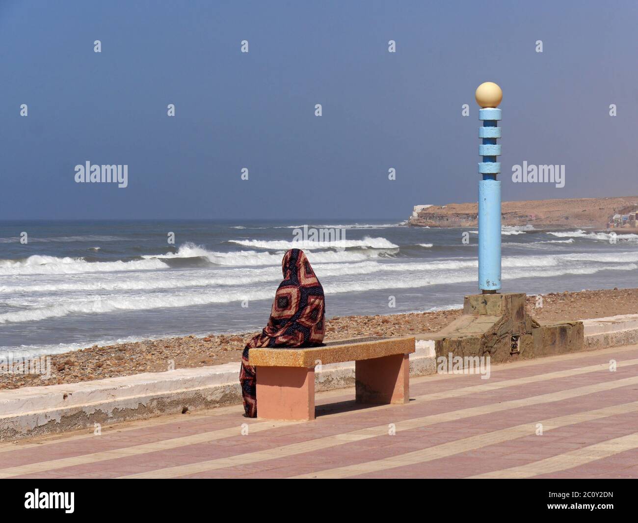 Muslim sitzt auf einer Bank an der Atlantikküste in Aglou Plage, Marokko Stockfoto