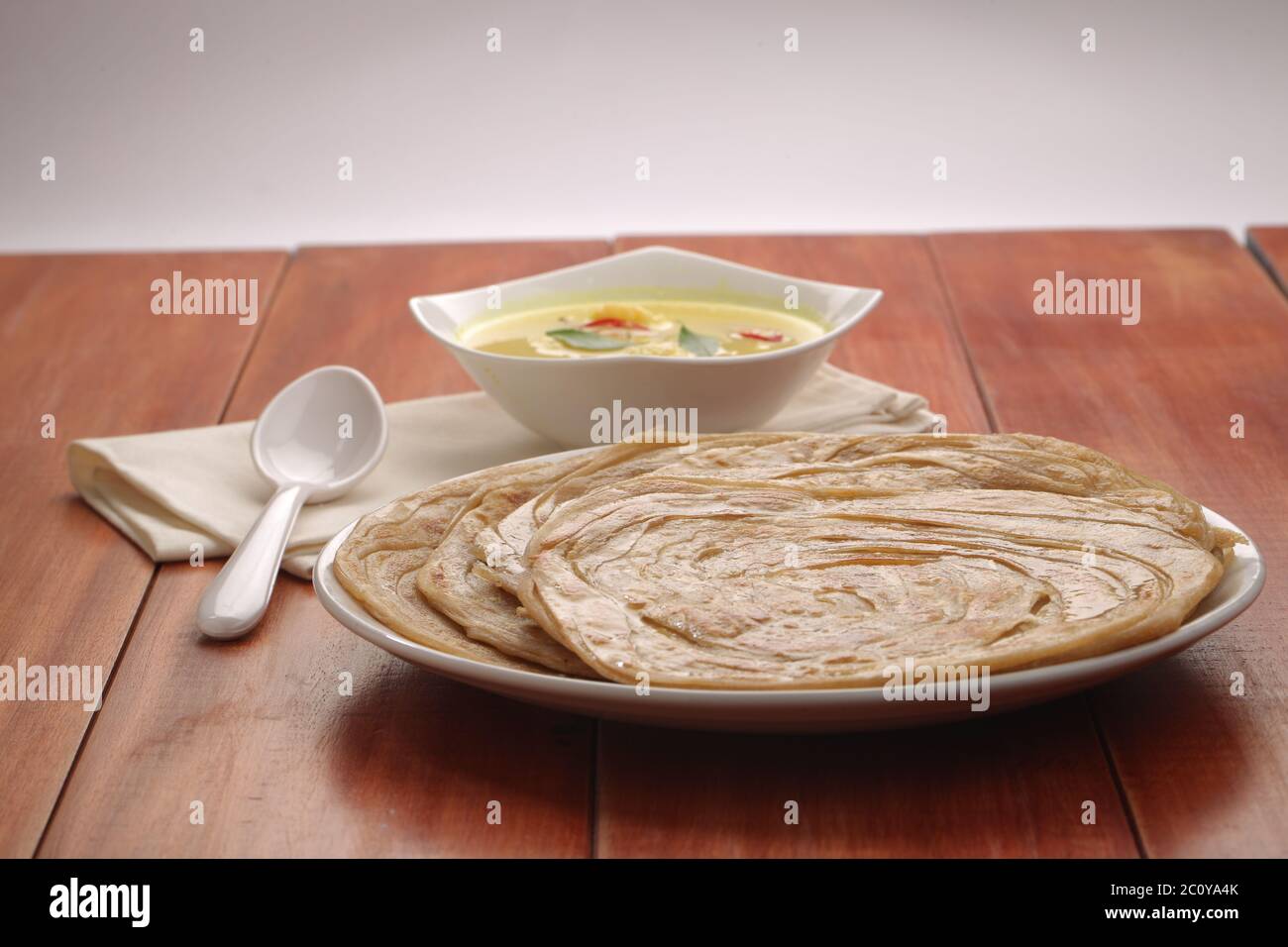 Hausgemachtes Kerala Parotta/Porotta/Paratha/geschichtetes Flachbrot mit Weizen, beliebt in Südindien, serviert in einem Holzbrett mit braunem Holzhintergrund Stockfoto