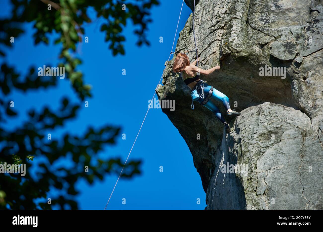 Tapfere Dame Alpinist in Sportbekleidung Klettern extrem vertikalen Felsen  unter schönen blauen Himmel. Frau Bergsteigerin, die hohen Berg aufsteigt  und versucht, den Gipfel zu erreichen. Konzept des Extremsports  Stockfotografie - Alamy