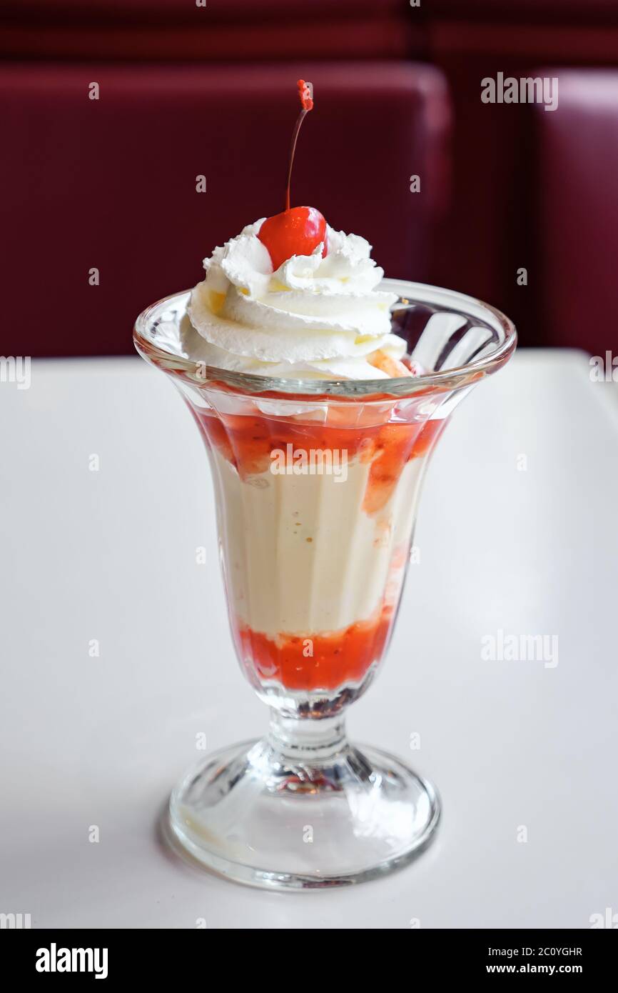 Eis mit Erdbeersirup und Schlagsahne in einem Glas. Stockfoto
