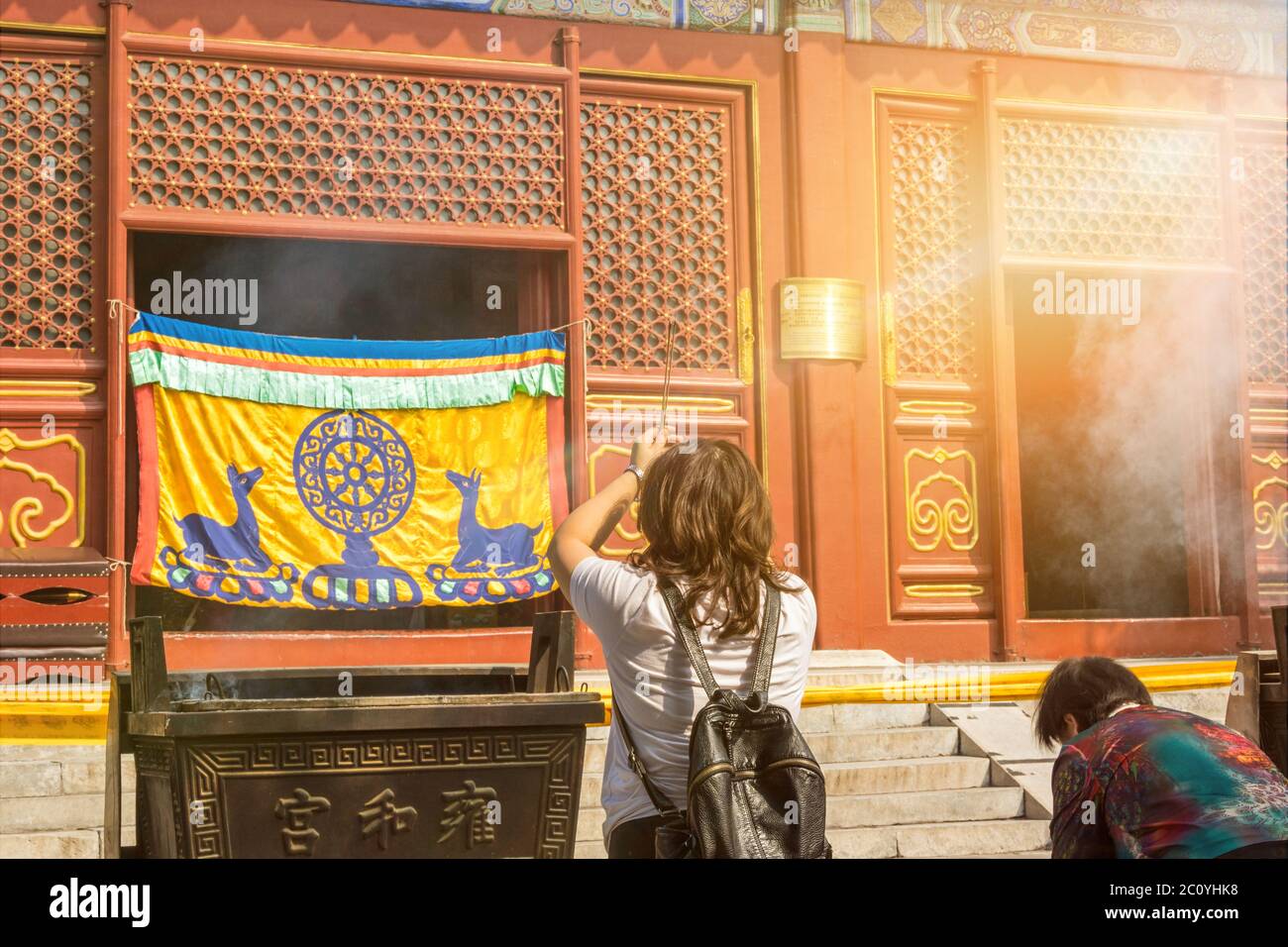 Asiatische Frau verehrt mit Räucherstäbchen an einem bunten buddhistischen Tempel Stockfoto