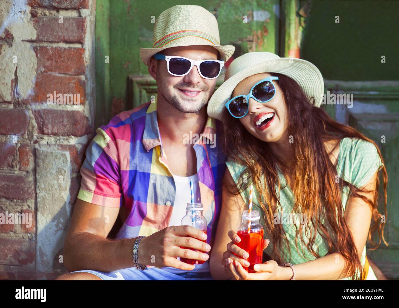 Glückliches junges Paar in der Straße mit Hüten und Sonnenbrillen Stockfoto