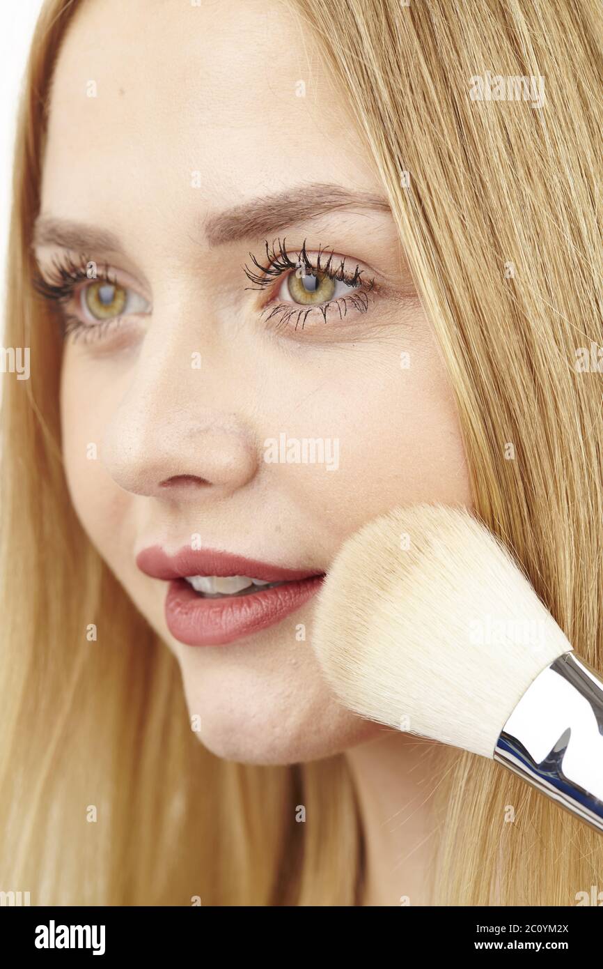 Blonde junge Frau verwendet Pinsel zu Pulver Stockfoto