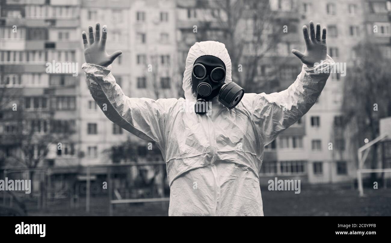 Zentrierte schwarz-weiße Momentaufnahme eines Mannes, der vor einem hohen Wohnblock steht und Stoppschild mit beiden Händen nach oben zeigt Stockfoto