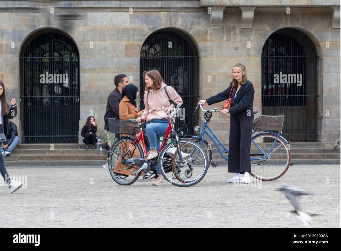 Mädchen mit Fahrrädern vor dem Königspalast, Amsterdam, Niederlande Stockfoto