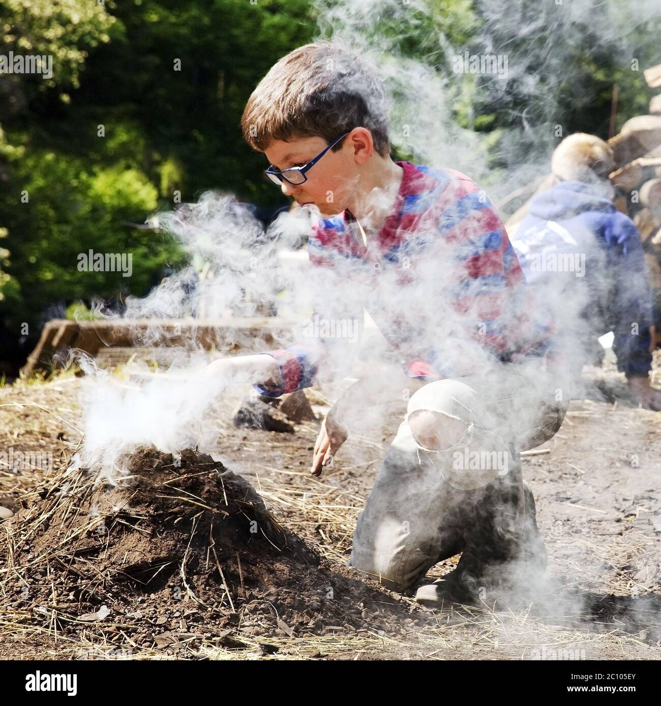 Jungen mit Rauchen Holzkohle Pile, Ennepetal, Ruhrgebiet, Nordrhein-Westfalen, Deutschland Stockfoto